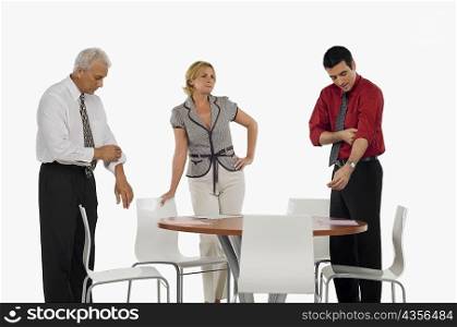 Two businessmen folding their shirt sleeves with a businesswoman standing beside them