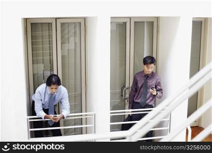 Two businessmen holding mobile phones