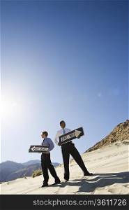 Two Businessmen Holding One Way Signs in the Desert