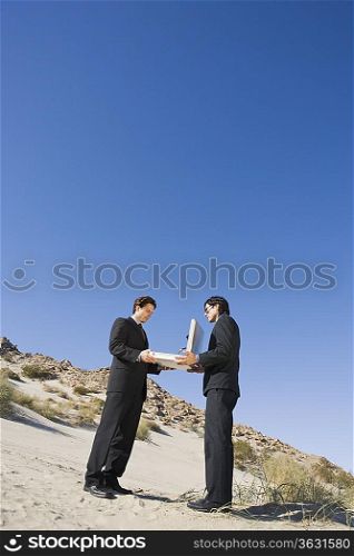 Two Businessmen Holding Open Briefcase in the Desert