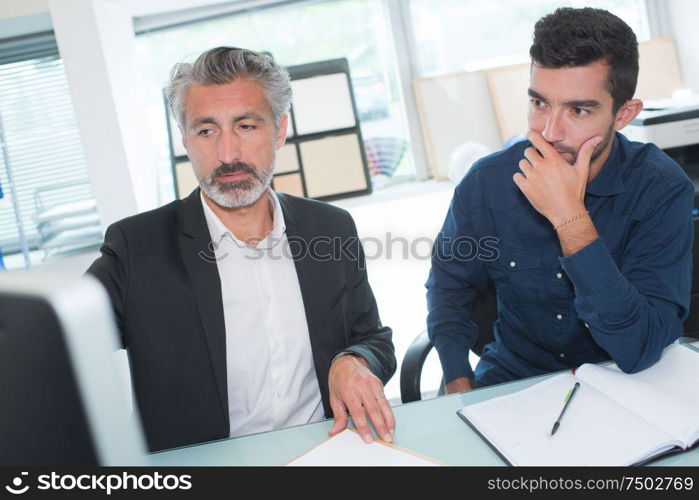 two businessmen in fornt of computer in office