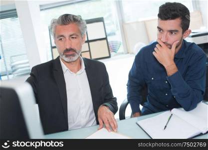 two businessmen in fornt of computer in office
