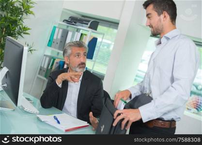 two businessmen in fornt of computer in office