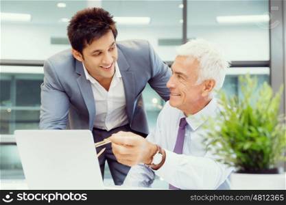 Two businessmen in fornt of computer in office. Working together effectively