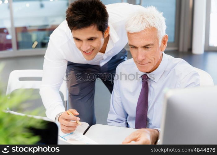 Two businessmen in fornt of computer in office. Working together effectively