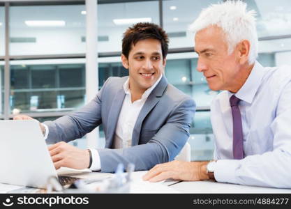 Two businessmen in fornt of computer in office. Working together effectively