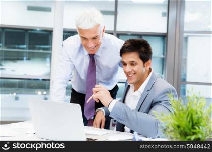 Two businessmen in fornt of computer in office. Working together effectively