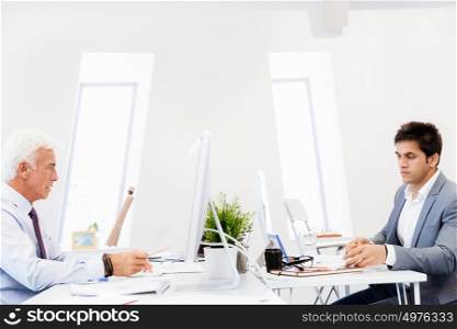 Two businessmen in fornt of their computers in office. Working together effectively