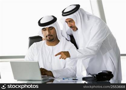 Two businessmen in office pointing at laptop (high key/selective focus)