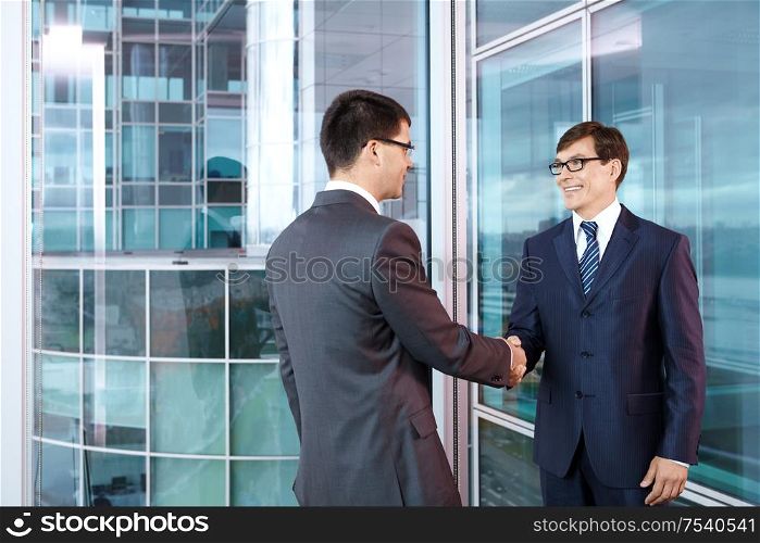 Two businessmen in office shake hands