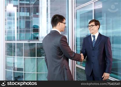 Two businessmen in office shake hands