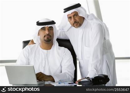 Two businessmen in office with laptop (high key/selective focus)