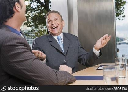 Two businessmen laughing in a conference room