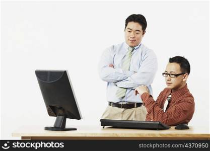 Two businessmen looking at a flat screen monitor