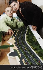 Two businessmen looking at an architectural model in an office and discussing