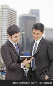 Two Businessmen Looking at Note Pad