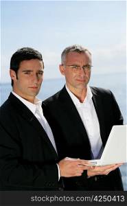 Two businessmen outdoors with laptop