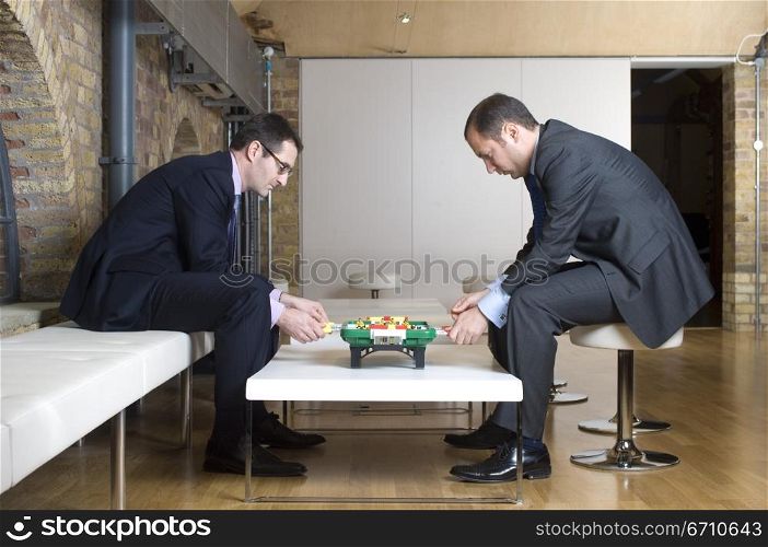 Two businessmen playing foosball