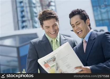 Two businessmen reading a magazine and smiling