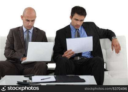 Two businessmen reading through presentation