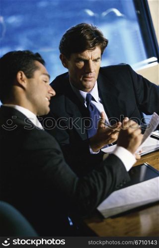 Two businessmen seated at a table in an office