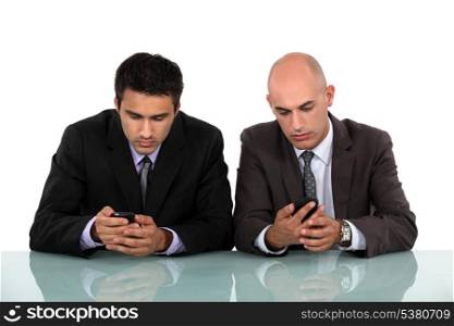 Two businessmen sending text messages