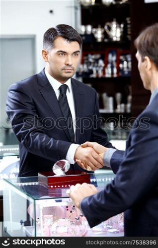 Two businessmen shake hands on a forward background