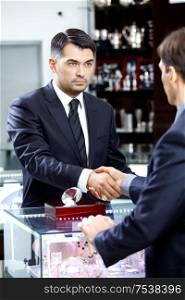 Two businessmen shake hands on a forward background