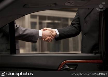 Two businessmen shaking hand through car window