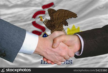 two businessmen shaking hands after good business investment agreement in america, in front US state flag of illinois
