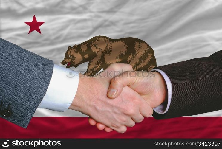 two businessmen shaking hands after good business investment agreement in america, in front US state flag of california
