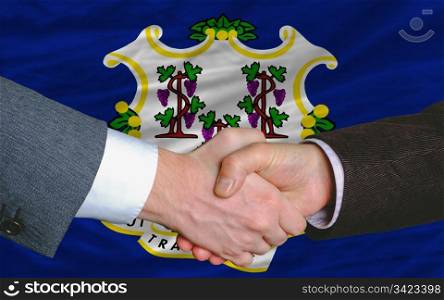 two businessmen shaking hands after good business investment agreement in america, in front US state flag of connecticut