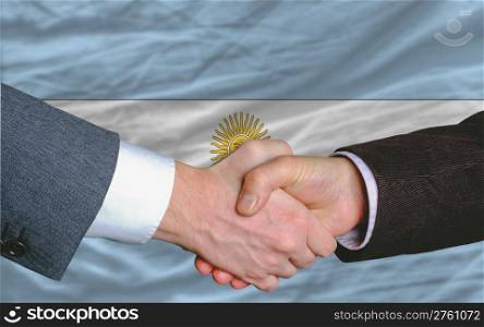 two businessmen shaking hands after good business investment agreement in argentina, in front of flag