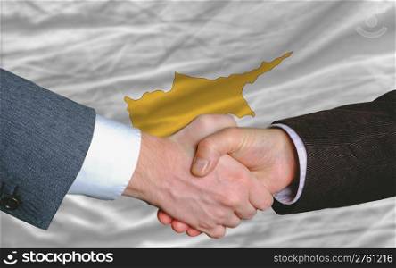 two businessmen shaking hands after good business investment agreement in cyprus, in front of flag
