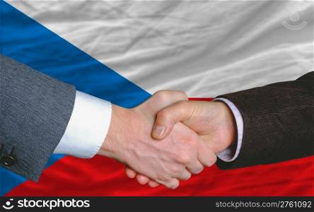 two businessmen shaking hands after good business investment agreement in czech, in front of flag