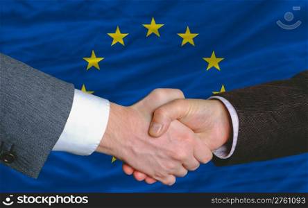 two businessmen shaking hands after good business investment agreement in europe, in front of flag