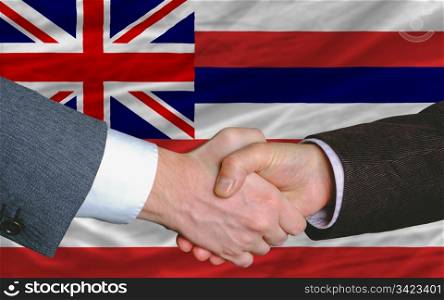two businessmen shaking hands after good business investment agreement in front US state flag of hawaii