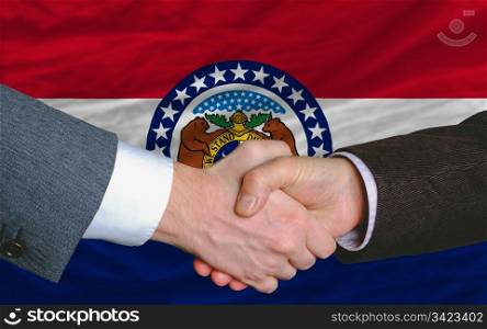 two businessmen shaking hands after good business investment agreement in front US state flag of missouri