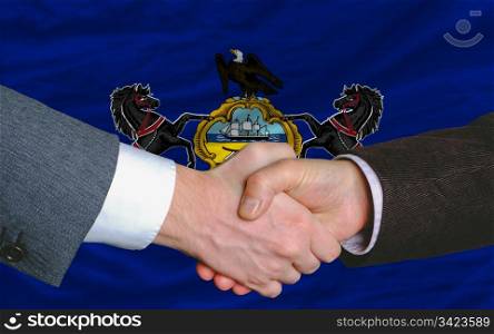 two businessmen shaking hands after good business investment agreement in front US state flag of pennsylvania