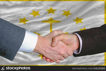 two businessmen shaking hands after good business investment agreement in front US state flag of rhode island