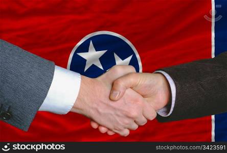 two businessmen shaking hands after good business investment agreement in front US state flag of tennessee