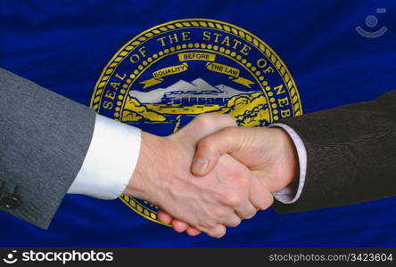two businessmen shaking hands after good business investment agreement in front US state flag of nebraska