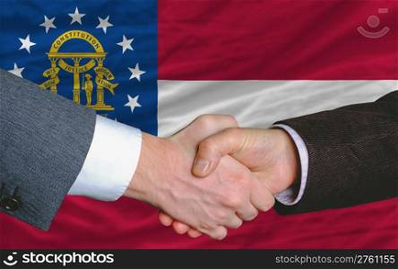 two businessmen shaking hands after good business investment agreement in georgia, in front of flag