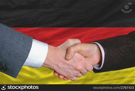 two businessmen shaking hands after good business investment agreement in germany, in front of flag