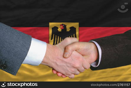 two businessmen shaking hands after good business investment agreement in germany, in front of flag