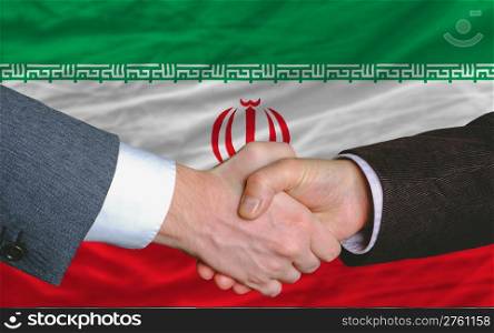 two businessmen shaking hands after good business investment agreement in iran, in front of flag