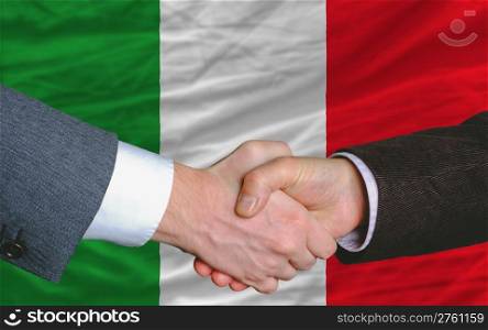two businessmen shaking hands after good business investment agreement in italy, in front of flag