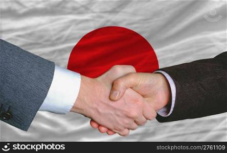 two businessmen shaking hands after good business investment agreement in japan, in front of flag
