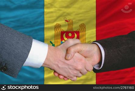 two businessmen shaking hands after good business investment agreement in moldova, in front of flag