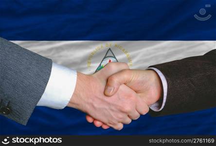 two businessmen shaking hands after good business investment agreement in nicaragua, in front of flag